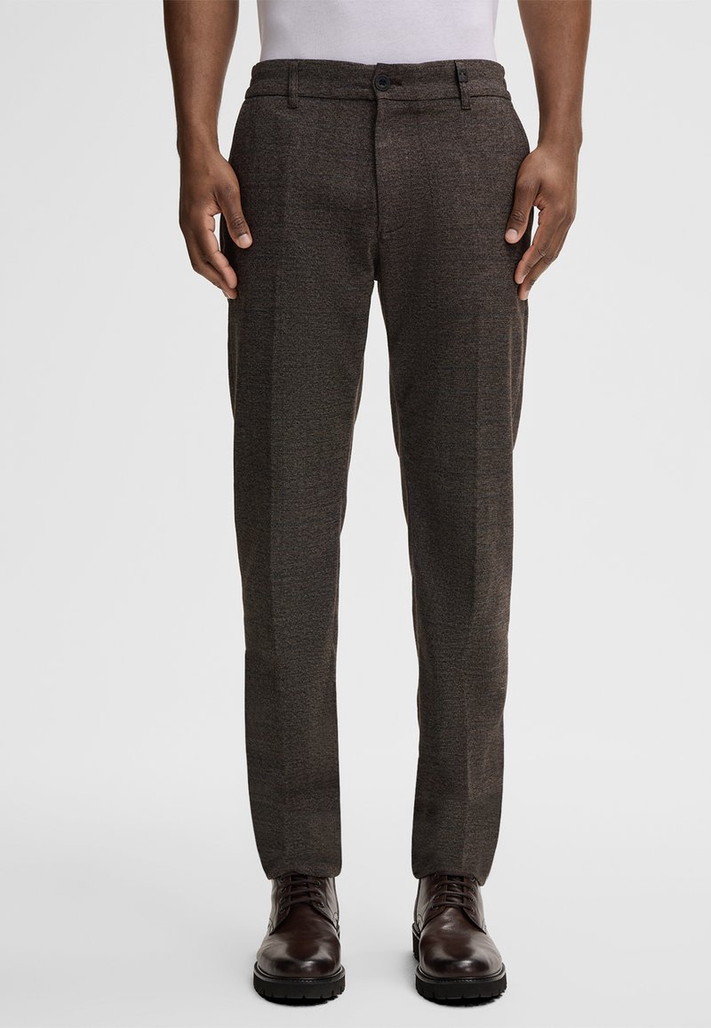 Brązowe, teksturowane spodnie o slim fit, z zapięciem na guzik i bocznymi kieszeniami. W komplecie z ciemnymi butami eleganckimi.