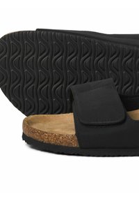 Sort sandal med en korksål, Velcro-rem og gummisål med bølget mønster. Glat syntetisk overdel og naturlig tekstur.