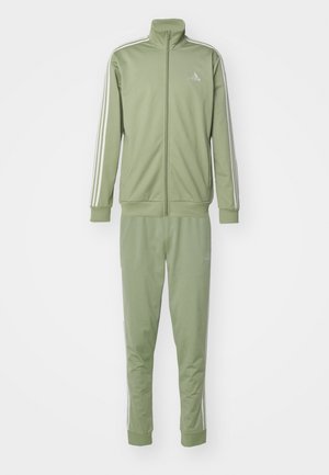 Tuta sportiva verde in tessuto liscio, con giacca a zip intera e collo alto abbinata a pantaloni con strisce laterali bianche.