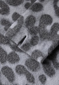 Tessuto grigio del maglione con stampa leopardata in grigio scuro, caratterizzato da una superficie morbida e testurizzata e un piccolo dettaglio con spacco.