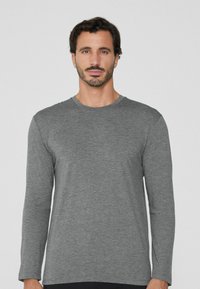 Graues Langarmshirt aus weichem Stoff mit Rundhalsausschnitt. Verfügt über eine lockere Passform und einen leicht abgerundeten Saum, minimale Nähedetails.