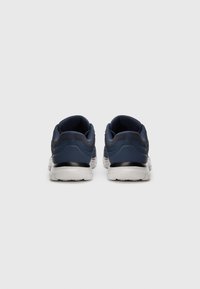 Pair of navy blue athletic shoes with white soles shown from the back on a plain light gray background.
