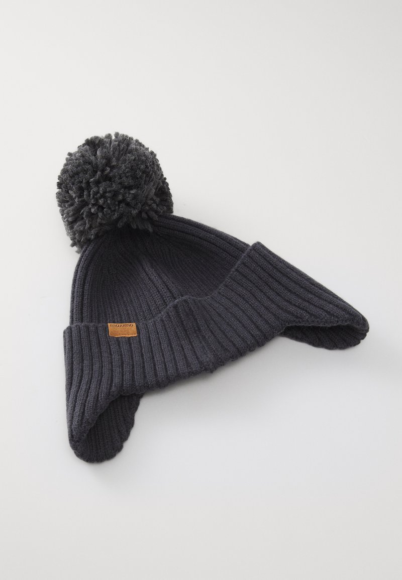 Cappello in maglia a coste grigio scuro per l'inverno, con alette per le orecchie e un grande pompon sulla parte superiore, dotato di un piccolo etichetta "maximo" marrone sul risvolto.