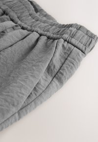 Grau elastische Taillenshorts aus weichem Stoff, mit Bügelfalten und leicht zerknitterter Textur. Der Saum ist sauber verarbeitet.