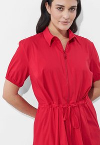 Rotes kurzärmliges Kleid mit Kragen und Frontreißverschluss. Verfügt über einen elastischen Bund und eine Bindedetail, gefertigt aus glattem Stoff.
