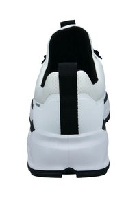 Weißer Sneaker von hinten betrachtet, mit einem schwarzen Zugtab, dicker Sohle und schwarzem Innenfutter.