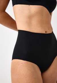 Højprovokerede sorte badedragtbukser lavet af glat stof, med sømløse kanter og et enkelt design uden yderligere mønstre eller hardware.