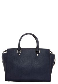 Marinblå handväska med texturerad utsida, dubbla övre handtag och silverfärgade detaljer. Rektangulär form med vinklade sidopaneler.