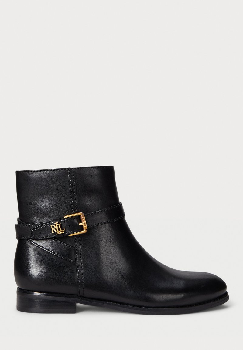 Bota de tornozelo em couro preto com um salto baixo, apresentando um detalhe com fivela em metal dourado e costura ao redor do tornozelo.