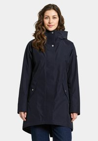 Marinblå vattentät jacka med hög krage, långa ärmar och två sidofickor med tryckknappar. Slät textur, knälång design.