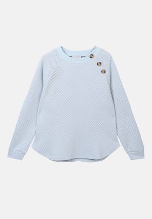 Jasnoniebieska koszula z długim rękawem o teksturowanym geometrycznym wzorze. Posiada okrągły dekolt i trzy dekoracyjne guziki na ramieniu.