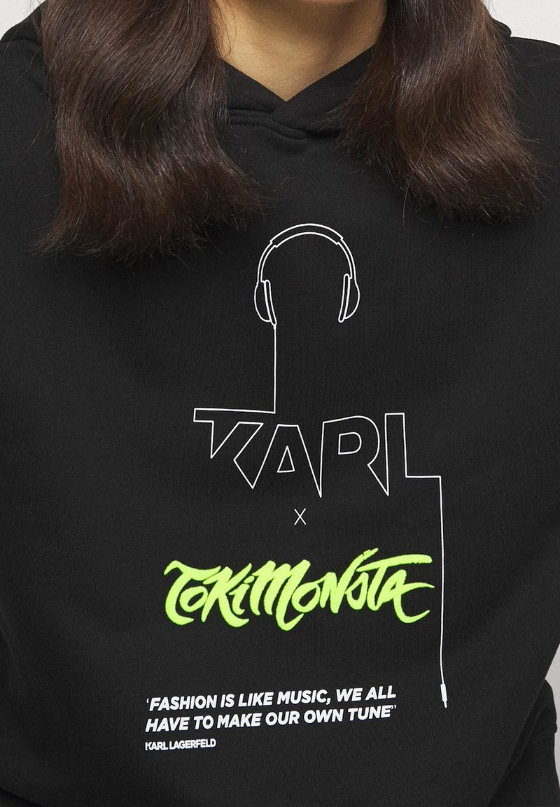 Sweat à capuche noir avec le texte « KARL x Tokimonsta », un graphique de casque audio et une citation "La mode est comme la musique, nous devons tous créer notre propre mélodie."