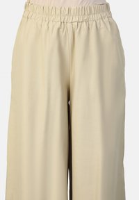 Beige wide-leg pants with an elastic waistband, smooth texture, and a loose fit, providing comfort and ease of movement.