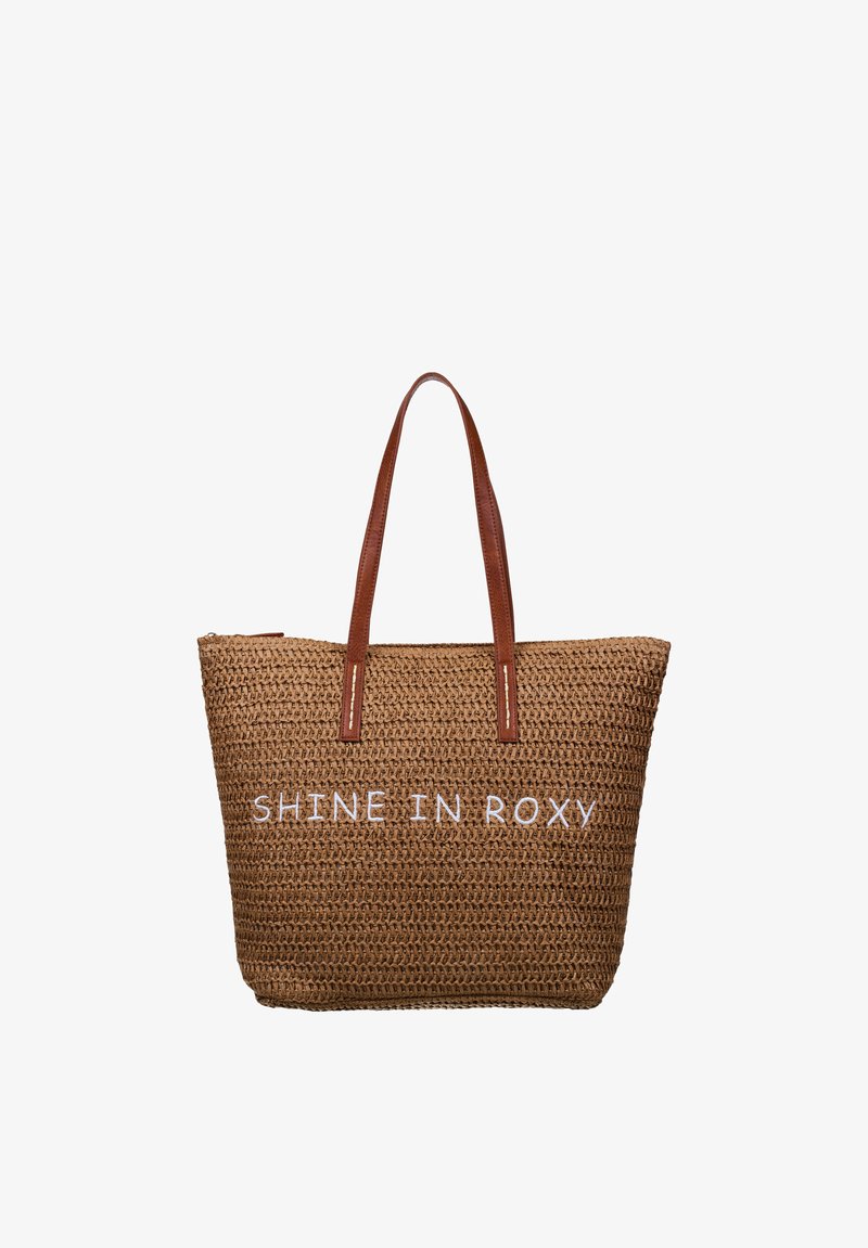 Sac fourre-tout tissé marron avec deux anses en cuir marron et texte blanc brodé "SHINE IN ROXY" à l'avant.