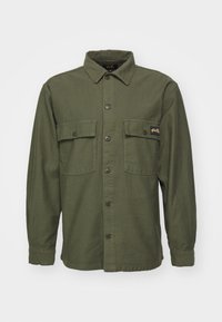 Olive green shirt jacket made of cotton, featuring a pointed collar, two chest pockets, front button closure, and long sleeves.