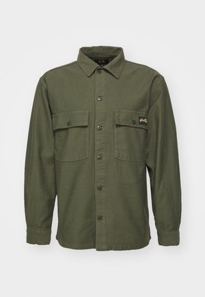Olive green shirt jacket made of cotton, featuring a pointed collar, two chest pockets, front button closure, and long sleeves.