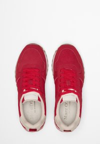 Czerwone sneakersy z tkaniny o fakturowanym wykończeniu, białe sznurowadła i beżowy akcent na języku. Gumowa podeszwa z delikatnym wzorem.