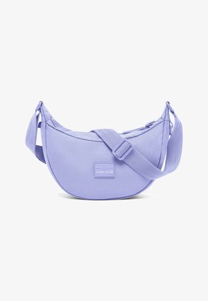 Sac d'épaule en tissu violet de forme arrondie, avec une bandoulière réglable et une étiquette à l'avant. Texture lisse et design minimaliste.