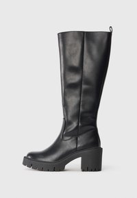 Knee-high black leather boots with a smooth texture, chunky rubber heel, and lug sole. Features a pull tab for easy wear.