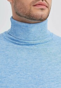 Pull bleu clair à col roulé en côte, fabriqué à partir d'un tissu doux, présentant un col épais et une texture lisse, idéal pour un look décontracté.
