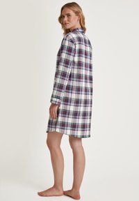 Camicia da notte a quadri in bianco, blu, verde e rosso. Maniche lunghe, colletto con bottoni e lunghezza fino a metà coscia, realizzata in tessuto morbido.