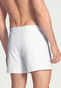 Boxer bianchi in cotone con fascia elastica in vita, caratterizzati da una lunghezza della gamba corta e una texture liscia. Nessun motivo o dettaglio visibile.