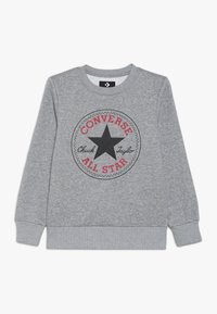 Sudadera gris con un logo redondo en negro y rojo de Converse All Star que presenta una estrella central. Los puños y el dobladillo acanalados añaden textura al diseño.