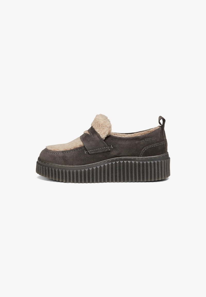 Chaussure à enfiler en daim marron foncé avec semelle épaisse nervurée, doublure en polaire beige et détail d'une bride sur le dessus.