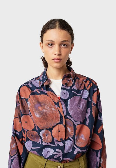 Camicia button-up multicolore con sfondo blu navy e grandi motivi floreali astratti in arancione e viola. Maniche lunghe e colletto strutturato.