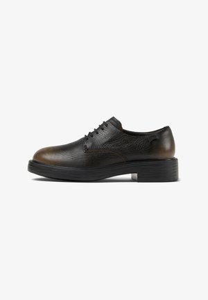 Zwarte leren schoenen met een gladde textuur, ronde neus en subtiele bruine accentueringen. Vetersluiting en dikke zwarte rubberen zool.