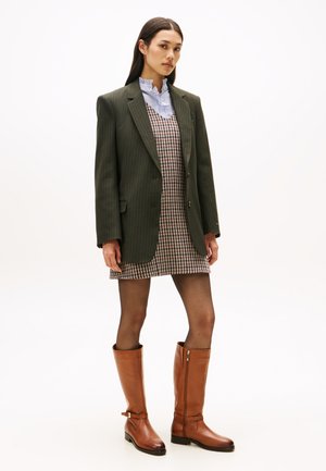 Stivali alti in pelle marrone, blazer a righe verdi, vestito stampato a zig zag e camicia a righe blu con colletto. Texture lisce.