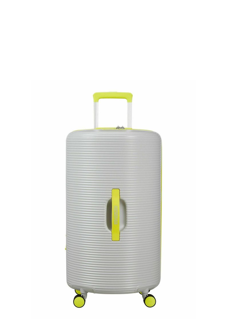 Valise rigide grise avec des rainures texturées, des accents jaunes, une poignée supérieure et quatre roues pivotantes jaunes pour une mobilité aisée.