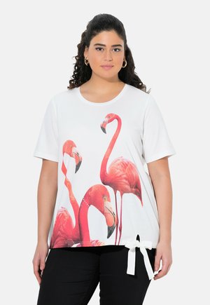 T-shirt blanc à manches courtes présentant des graphiques de flamants roses vibrants et un détail noué à l'ourlet. Tissu doux avec une coupe décontractée.