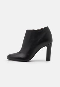 Sort læderankelstøvle med rundet tå og høj stilletthæl, der har en glat tekstur og minimalistisk design. Ingen fremtrædende accenter.