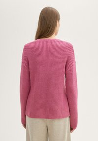 Maglione rosa lavorato a maglia con finitura testurizzata, maniche lunghe e collo rotondo. Presenta una vestibilità leggermente ampia e orlo a coste.
