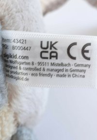 Clothing label showing UKCA and CE marks, brand sigikid, German address, eco-friendly production, and made in China details.