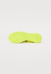 Lys gul skosål med en tekstureret overflade og cirkulære mønstre. Har et slankt design og er lavet af fleksibelt gummimateriale.