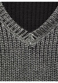Musta ja hopeinen neulottu paita, jossa on V-kaula-aukko, teksturoituja kuvioita ja kudottu resorikaulus.