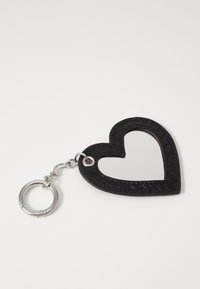Llave en forma de corazón negro con un espejo en el centro, con un borde de cuero texturizado y un anillo de metal plateado para su sujeción.