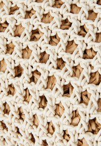 Woven basket made of natural fibers, featuring a light cream rope weave pattern over a textured, brown base with interwoven strands.