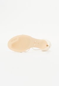 Cream-colored high-heeled shoe with a smooth finish, featuring a textured rubber sole and a subtle logo embossed on the bottom.