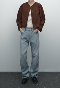 Brun stribede jakke med knapper, hvid skjorte, lyseblå jeans og sorte sko. Materiale: stof; pasform: afslappet; tekstur: glat.