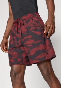 Μαγιώ σε μπορντώ και μαύρο σχέδιο με ρυθμιζόμενη ελαστική μέση και κορδόνι. Περιλαμβάνει πλαϊνές τσέπες και ραφές.