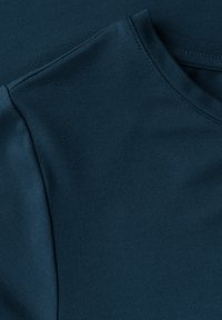 Ciemnoniebieska bawełniana tkanina o gładkiej teksturze. Posiada okrągły dekolt i przeszycia na ramionach.