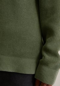 Pulover verde cu model tricotat cu dungi, având o textură cu model, tiv și manșete strânse și un finisaj neted și moale.