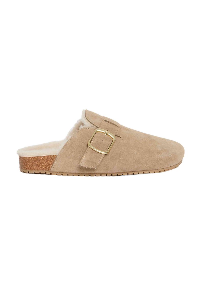 Pantufla de ante beige con forro de piel sintética, plantilla de corcho y un acento de hebilla de metal dorado. Diseño de perfil bajo con suela texturizada.