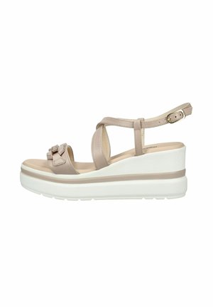 Sandalo beige con zeppa piattaforma, cinturino alla caviglia con fibbia, fasce incrociate sulla parte anteriore, fiocco decorativo sulla punta e suola spessa bianca.