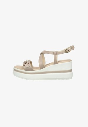 Sandalia de cuña plataforma beige con hebilla en el tobillo, tiras cruzadas en el frente, lazo decorativo en la puntera y suela blanca gruesa.