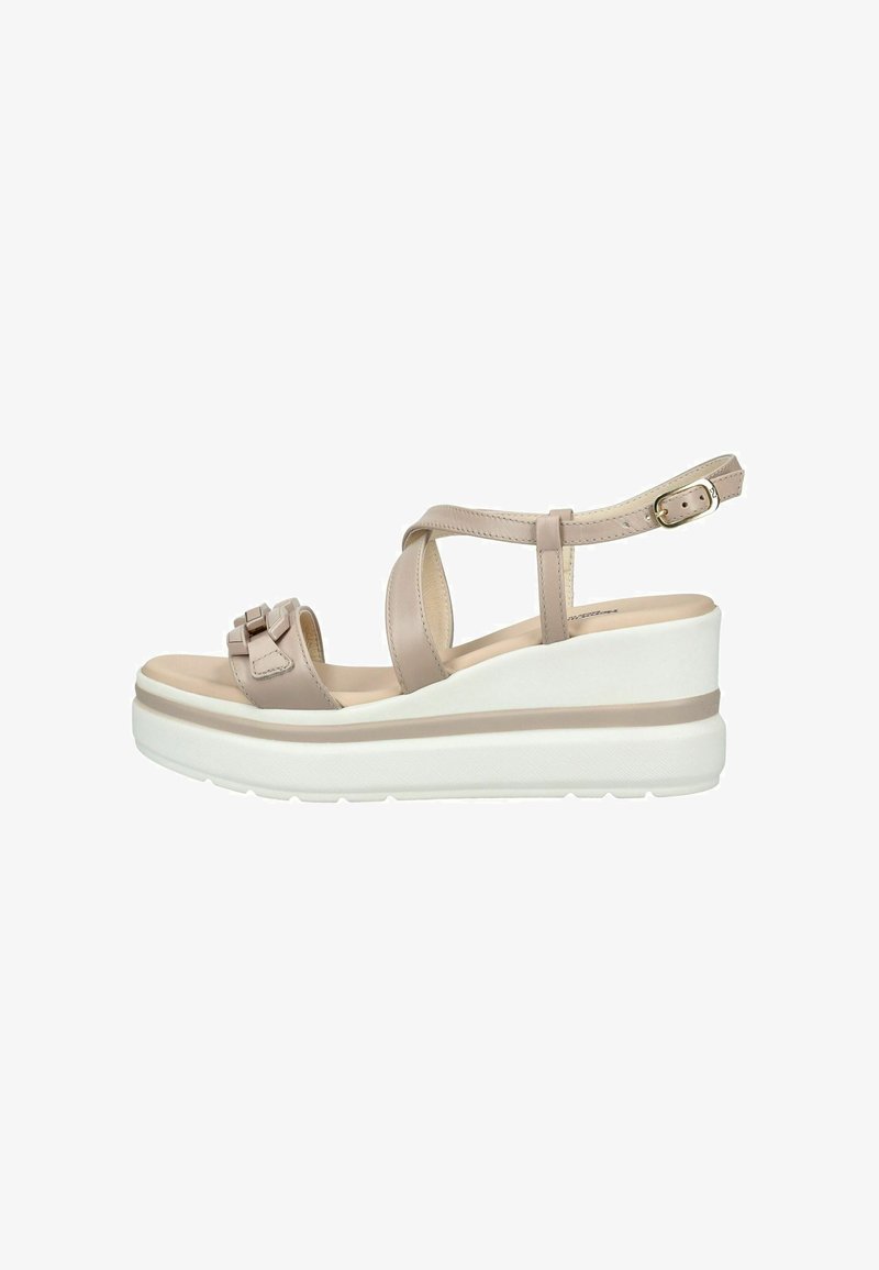 Sandale compensée beige avec bride à la cheville, brides croisées à l'avant, nœud décoratif sur le bout et semelle blanche épaisse.