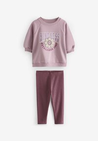 Rosa sweatshirt med blommig grafik, texten "Vänlighet etablerad 1982" och ribbade muddar, ihopparad med mörkrosa ribbade leggings.